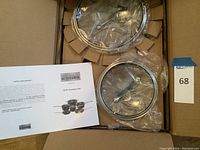 Opened box showing cookware set packed inside with clear plastic covers on lids and an information/warranty sheet included.