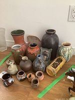 Overall image of 11 pottery vases in various shapes, colors and sizes, ranging from tall to short, showing diversity of the lot.