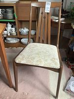Front view of a solid wood dining chair showing floral upholstered seat and decorative slatted backrest