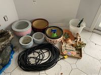 Photo showing all items in lot including jardinieres, pail, hose, garden plaques, spade and figures.