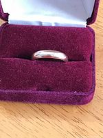 Ring displayed in red velvet presentation case, top view