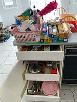 Birds-eye view showing multiple baskets and boxes on a kitchen counter with various cleaning liquids, food wrap boxes, and utensils visible.
