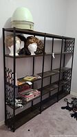 Full view of vintage metal shelving unit with multiple faux wood shelves and black faux iron frame, items displayed on shelves including wig heads and boxes not included.