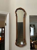 Front view of tall hall mirror showing detailed wood frame and reflective surface.