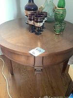 Top view of the wooden round table showing surface and decorative edge detail with a few glass and ceramic items placed on it.