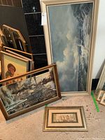 Overview of three framed art pieces including large ocean scene, war scene, and smaller print