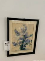 Full framed watercolour artwork hanging on a white wall, showing the floral painting and black simple frame with matting.