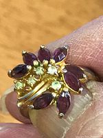 Front view showing cluster of marquise-cut purple stones and round white accents