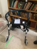 Front view of the Nexus rollator showing padded handlebar, seat with manual, and front caster wheels.