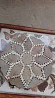 Photo of round trivet made of stitched skin pieces with geometric star pattern.