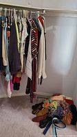 Photo of women's assorted dress clothes hanging on rack including tops, dresses, and knit sweaters.