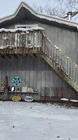 Outdoor scene showing the bench, chairs, and various garden art placed against a wall and under wooden stairs with snow on ground. Includes two wooden signs with 'Art Deco' and 'Funky' text.