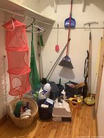 Image of corner of room showing hanging mesh organizer, broom, dustpan, baskets, cleaning items on floor