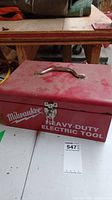 Red Milwaukee heavy-duty electric tool box with latch and handle for carrying, showing prominent Milwaukee logo.