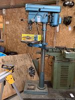 Full view of floor drill press on dolly base with mortising attachment box on table