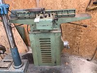 Front view of jointer on stand with drill press partially visible