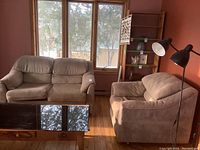 Living room setup showing the House of Braemore loveseat and armchair positioned by a window with a wooden floor and a black glass coffee table.
