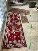 Three area rugs displayed on a carpeted floor near sliding glass doors, showing relative sizes and color contrasts.