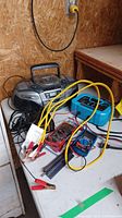 Photo of All Items: Next Echo portable stereo cassette player, Nautilus 12V battery charger, Innova and Mastercraft digital multimeters, yellow booster cables