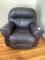Front view of dark brown bonded leather rocker recliner chair showing padded back, seat, and arms.