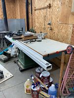 Full view of table saw with white top, aluminum guides and abrasive discs on surface