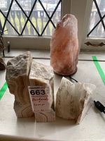 Photo showing two pairs of stone bookends and one salt lamp on a windowsill, with visible cord for lamp.