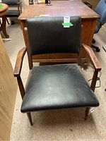 Front view of chair showing black vinyl seat and back with wooden frame