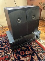 Photo of Energy E:XL speakers on top of Yamaha RX-396 receiver, showing front speaker grille and front panel of receiver with controls.