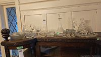 Full view of all glassware items arranged on a wooden table including decanters, bowls, glasses, and dishes.
