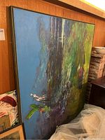 Front angled view of large painting showing abstract landscape with greens, blues, and purples on a stretched canvas and wooden frame leaning against wall.