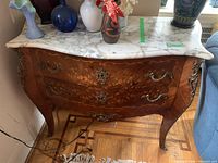 Front view of the commode showing bombé shape, marquetry and marble top