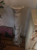 Front view of full pedestal showing round top, cylindrical shaft, carved vine detail