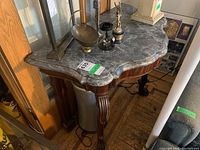 Frontal view of half-moon marble top and carved wooden legs