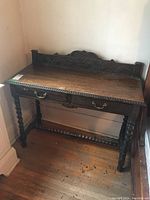 Full view of the vintage wooden table showing top, drawers, carved back panel and twisted legs.