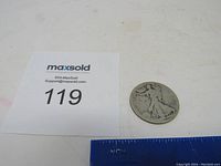 1917 Standing Liberty Half Dollar coin with ruler and inventory tag, showing overall coin size and condition.