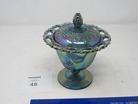 Full view of the colorful glass candy bowl with lid and pedestal base, showing grape and leaf designs and looped edge on lid.