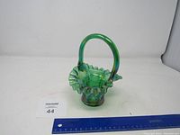 Front view of green glass basket with ruffled edge, handle, and grapevine etching