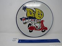 Front view of the round Esso metal sign showing two cartoon oil drops riding a scooter with Esso branding.
