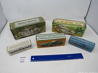 Five vintage car bottles in original boxes arranged with a ruler for scale