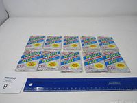 Front view of ten unopened 1992 Pacific Pro Soccer Plus trading card packs laid out in two rows on a white surface, a ruler included for scale.