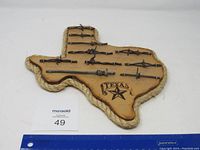 Full view of the Texas shaped plaque displaying multiple variety of mounted barbed wire samples, featuring rope trim and Texas star branding.