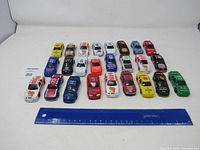 Overview photo showing all 25 Nascar diecast cars lined up in five rows of five against a white background with a blue ruler for scale.