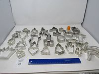 Full display of 27 metal and one small plastic cookie cutters arranged with a ruler showing size.