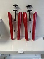 Two sets of red plastic boot trees/shapers with black handles, displayed upright on a white surface with a plain background.