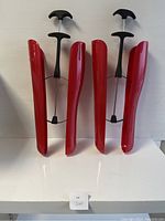 Pair of red plastic boot trees/shapers with black handles and spring wires for boots shape maintenance