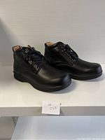 Side view of the pair of black ladies comfort shoes on display stand showing their shape and structure.