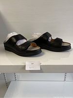 Left side angle view of the pair of black comfort shoes showing the adjustable straps and sole profile.