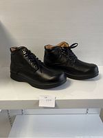 Side angled view of the pair of black leather comfort shoes showing lace-up design and cushioned collar.