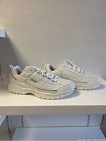 Side view of paired white Skechers shoes showing design details and sole pattern