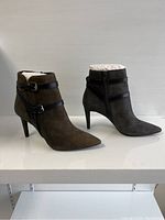 Side view of the pair of Michael Kors ankle boots showing pointed toe, black leather strap details, and mid-height heels.